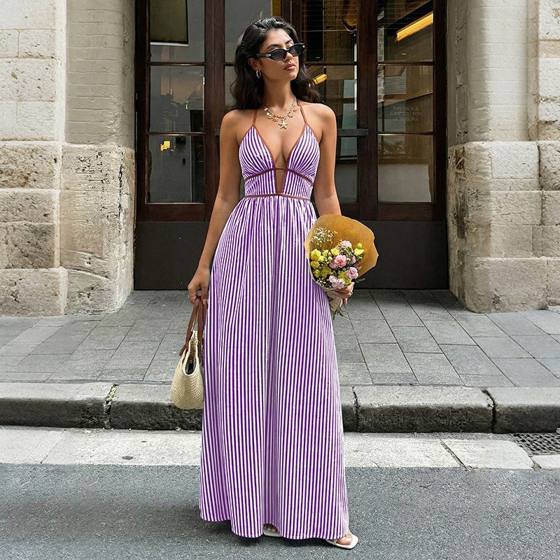 Woman in a green dress holding flowers and a handbag on a city street.