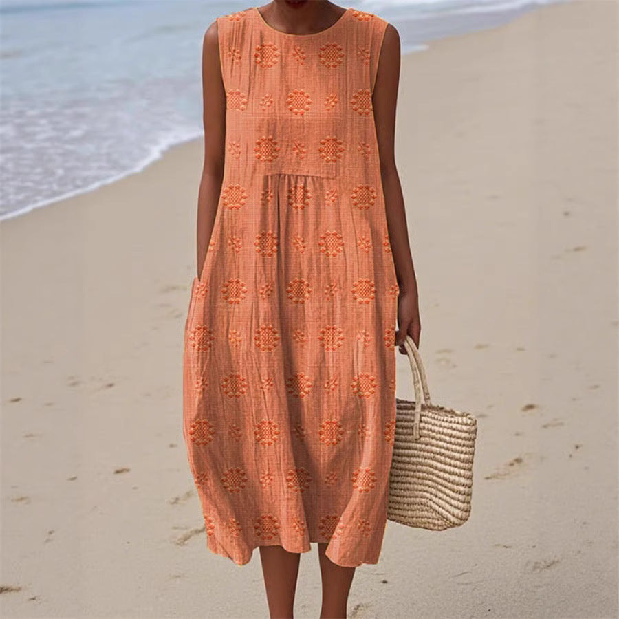 Woman in an orange dress standing on a beach with ocean in the background