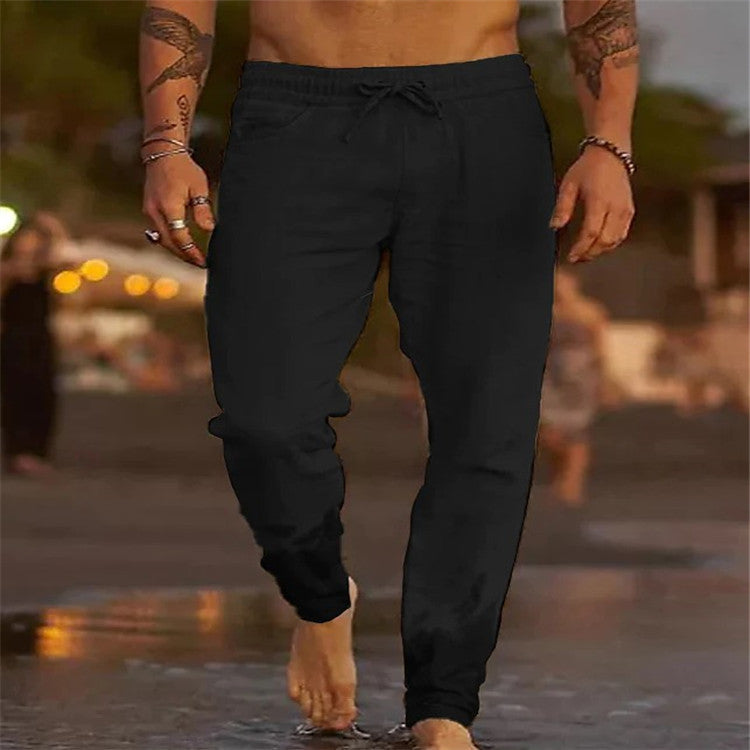 Person wearing black pants walking on a beach with a blurred background