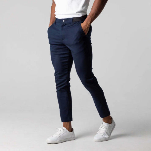 Person wearing navy pants and white sneakers on a plain background
