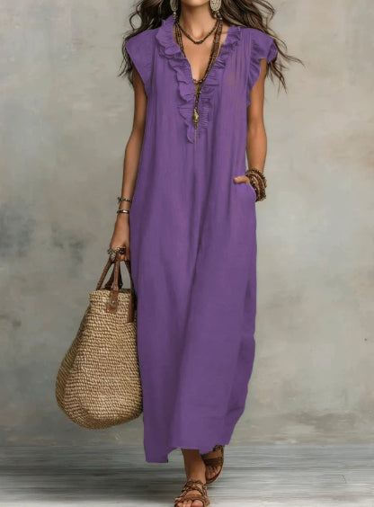 Woman wearing a purple dress holding a straw bag against a neutral background