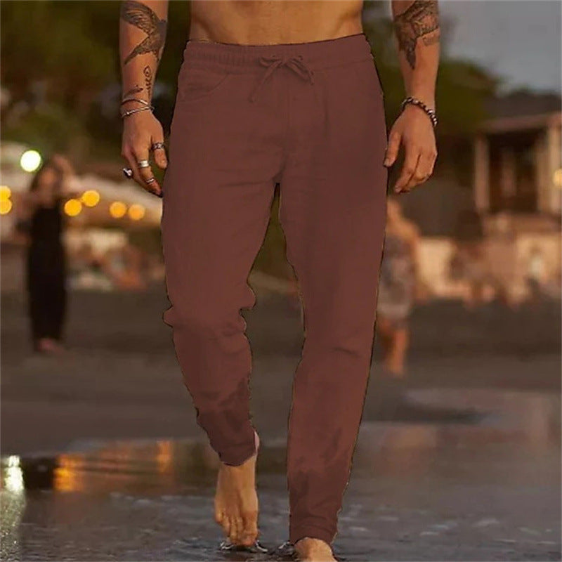 Person wearing maroon jogger pants walking on a beach with a blurred background