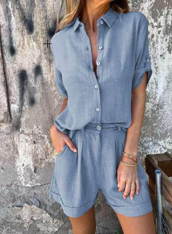 Woman wearing a light blue short-sleeve romper from ZA-Zola, standing against a textured wall.