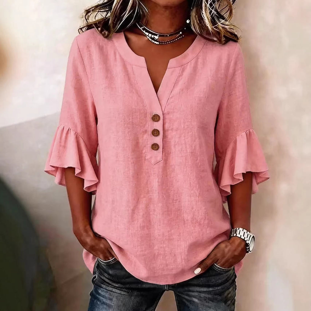 Person wearing a pink blouse with ruffled sleeves on a neutral background