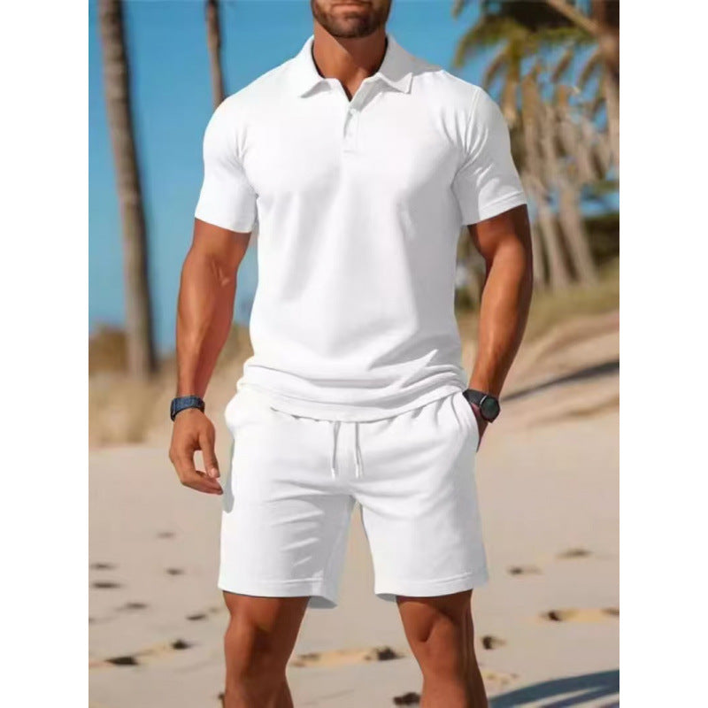 Man wearing a white polo shirt and shorts on a beach.