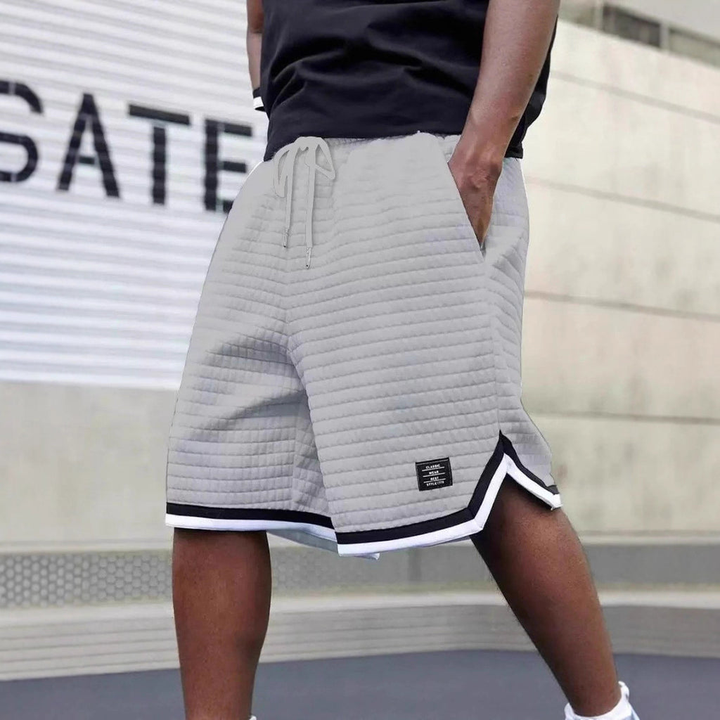 Person wearing gray shorts with a brand logo in front of a blurred background