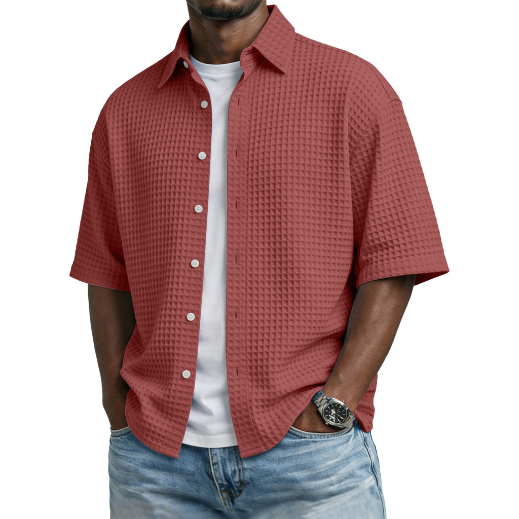 Man wearing a red textured shirt over a white t-shirt with blue jeans on a white background