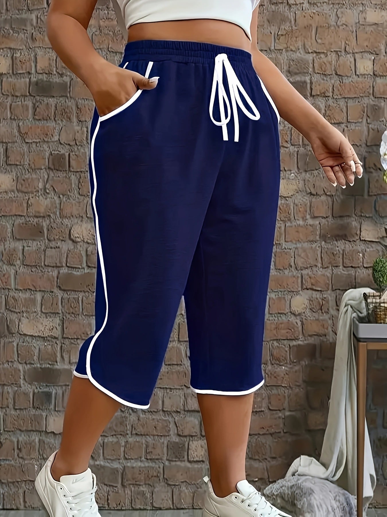 Person wearing navy blue shorts with white trim against a brick wall.