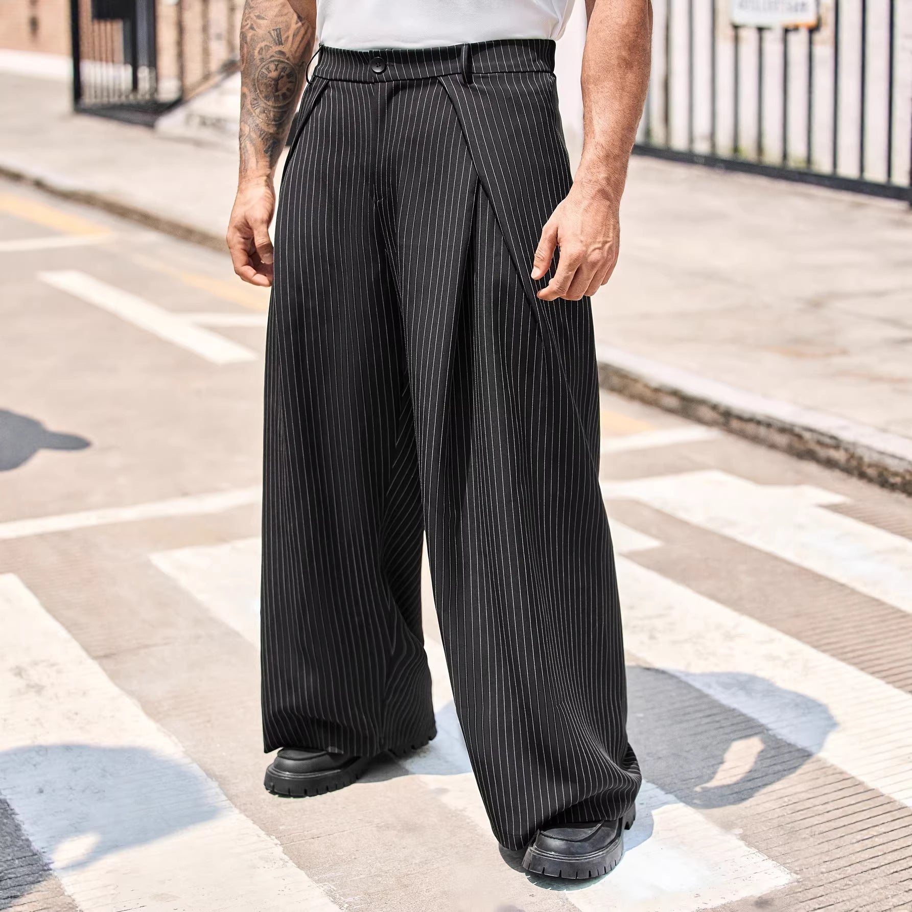 Person wearing black pleated wide-leg pants on a street.