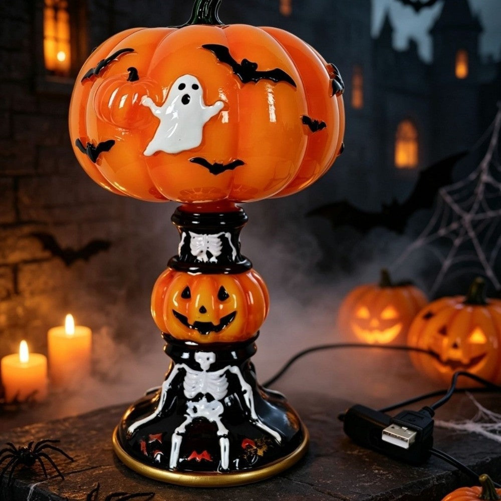 A Halloween-themed table lamp shaped like stacked pumpkins with skeleton and ghost details, shown lit on a dark tabletop with candles, cobwebs, and more pumpkins in the background.