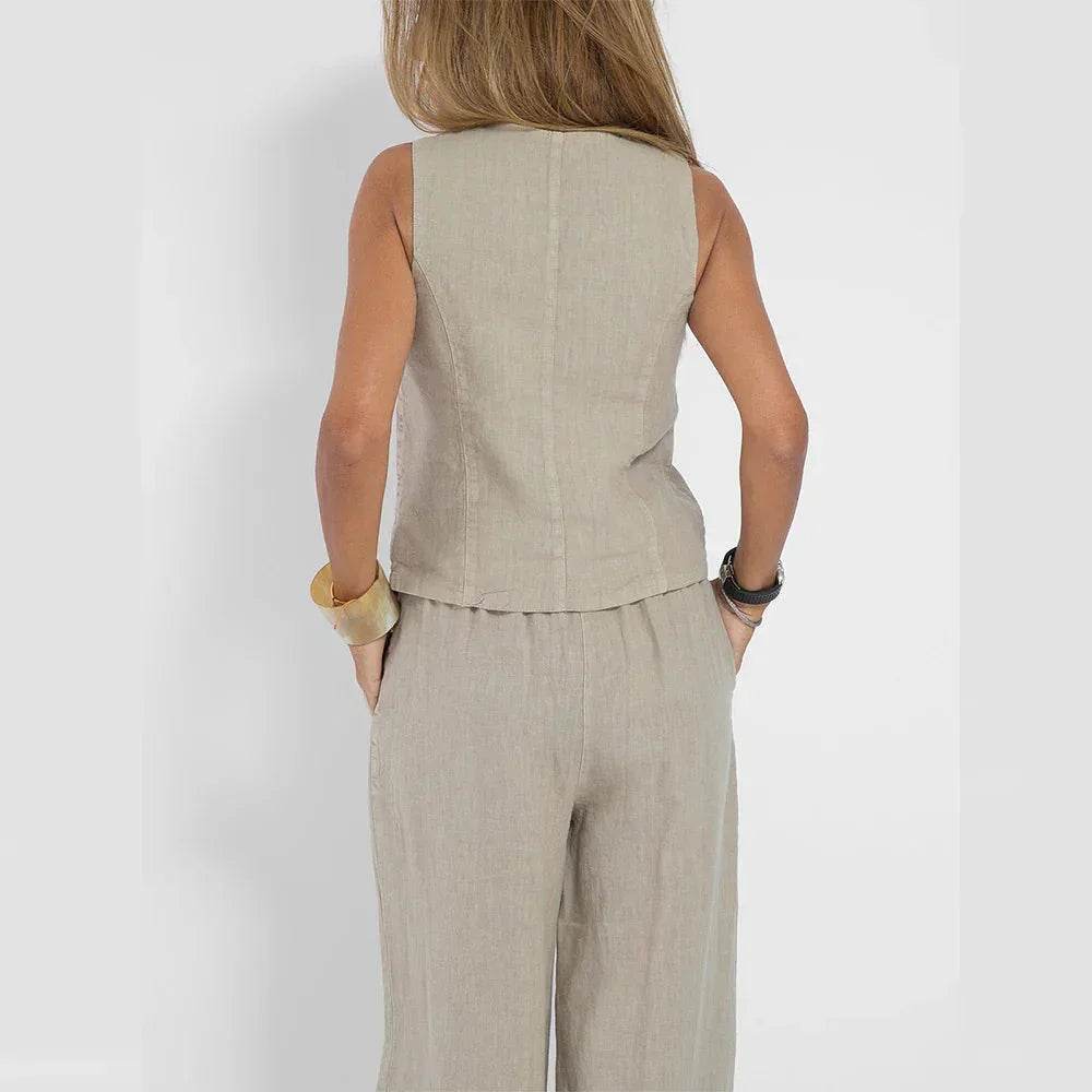 Woman in beige sleeveless linen jumpsuit by ZA-Zola, back view, neutral background