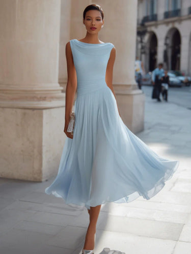 Woman in a light blue dress standing on a city street.
