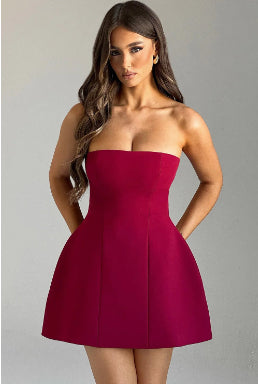 Woman wearing a strapless red dress against a plain background