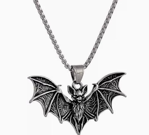 A silver-toned metal bat pendant necklace with intricate wing and body detailing, hanging from a matching chain against a plain white background.