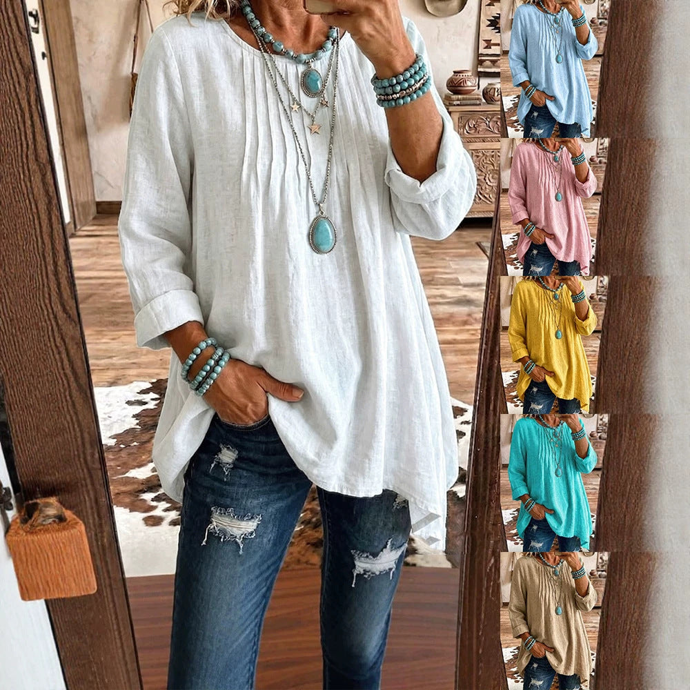 A woman takes a mirror selfie wearing a loose white linen-blend blouse with rolled sleeves, a high-low hem, and a long turquoise pendant necklace, paired with distressed blue jeans. A vertical strip on the right shows the same blouse in multiple colors (light blue, pink, yellow, teal, beige).