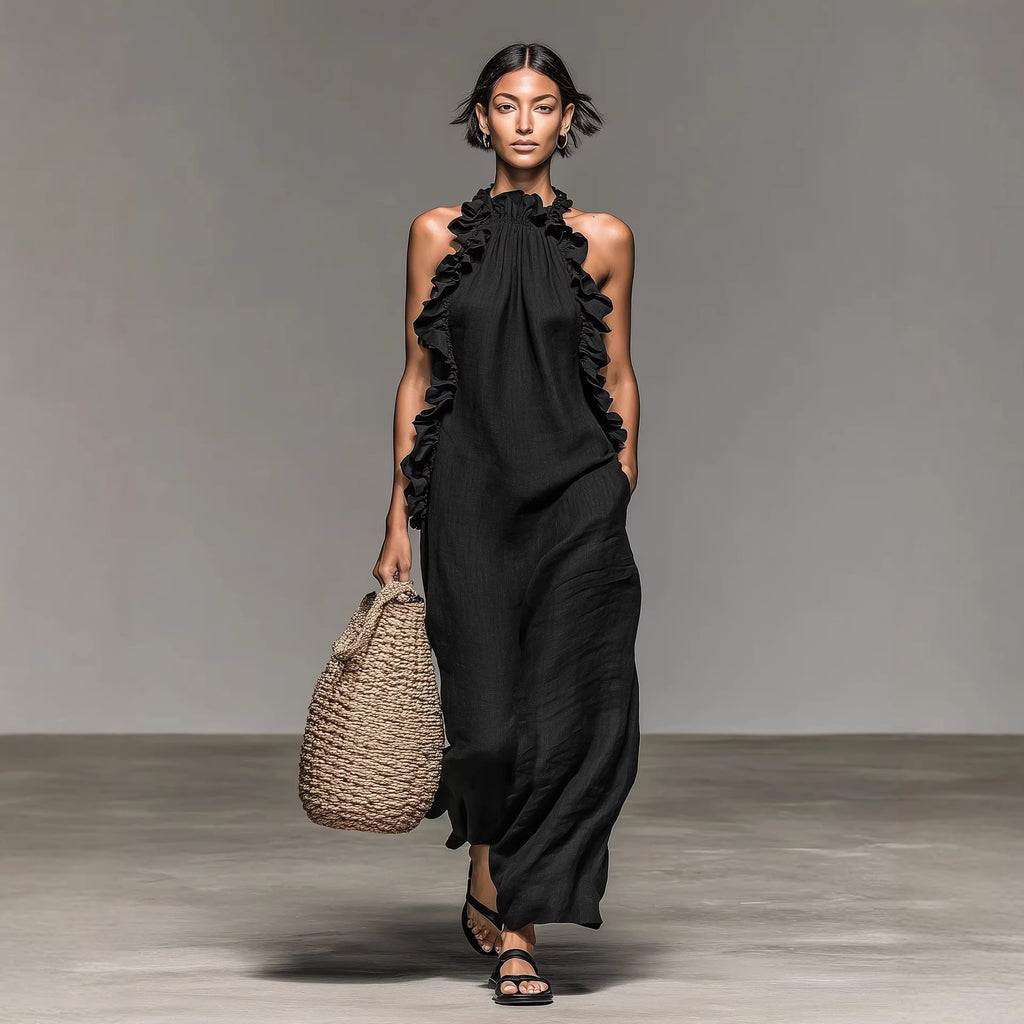 Model wearing a black dress with ruffles holding a woven bag on a plain background