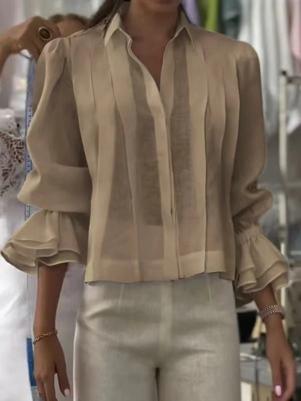 Beige blouse with ruffled sleeves worn by a person, blurred background