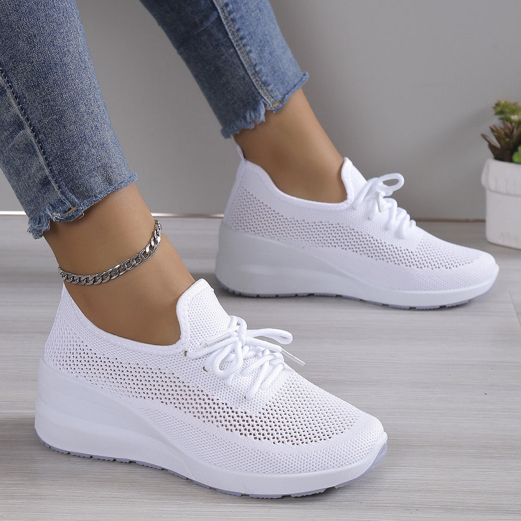 White sneakers worn with blue jeans on a neutral background