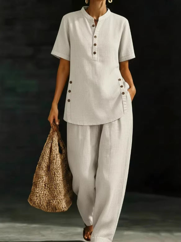 Person wearing a light gray outfit holding a woven bag against a dark background