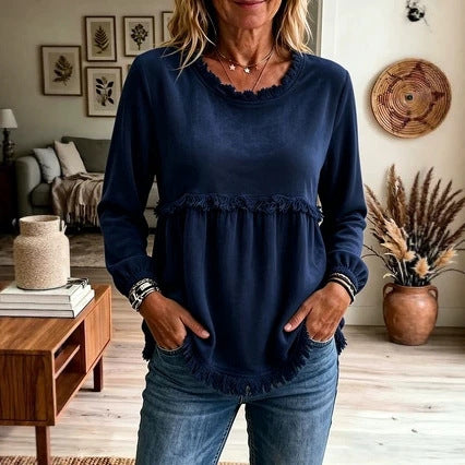 Woman wearing a navy blue top with ruffled details in a living room setting.