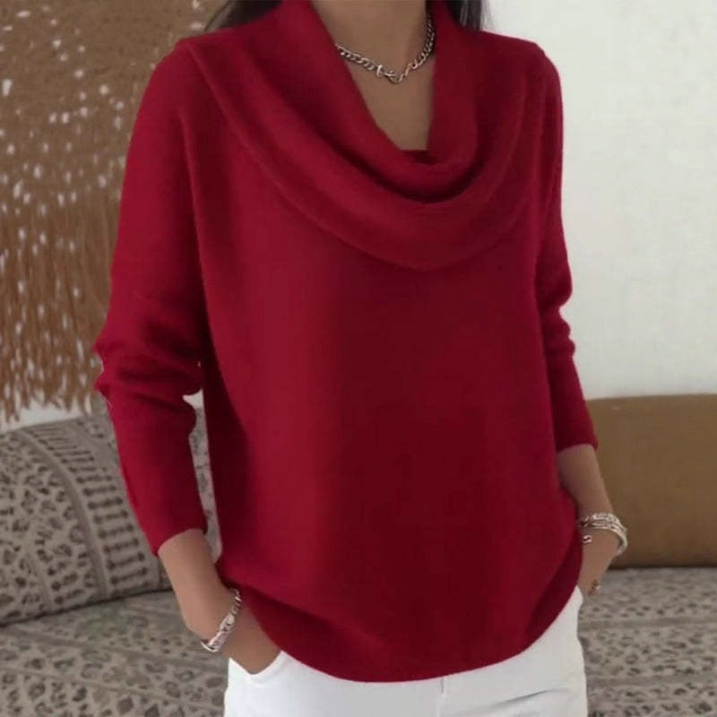Person wearing a red cowl-neck sweater with a neutral background