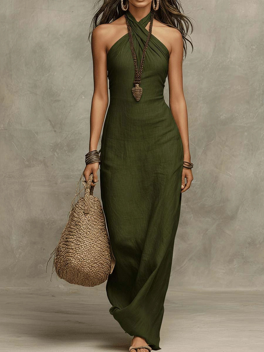 Woman wearing a green halter neck dress holding a woven bag against a neutral background
