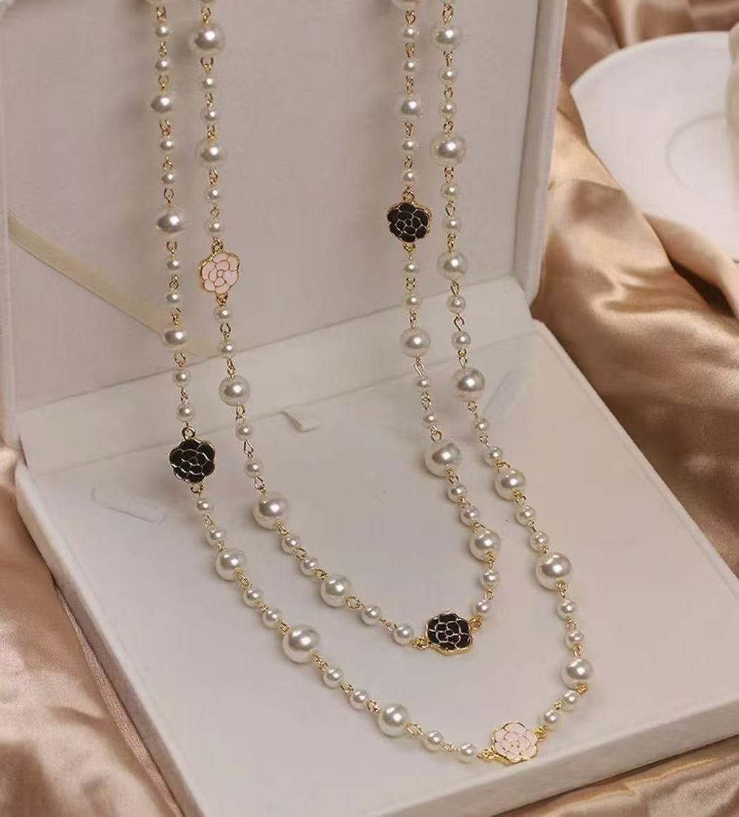 Pearl necklace with black clasp in a jewelry box on a beige fabric background