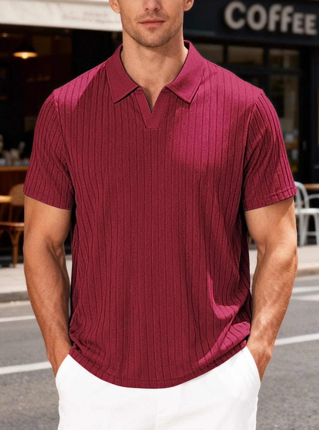 Man wearing a maroon polo shirt standing outdoors with a coffee shop in the background