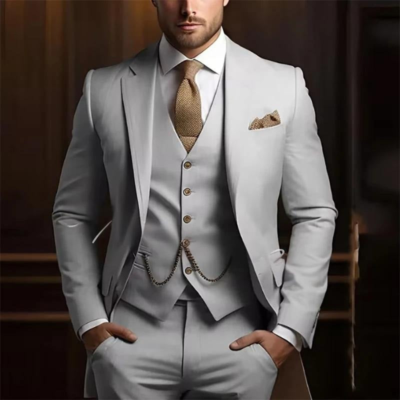 Man wearing a light gray suit with a brown tie and pocket square against a blurred background