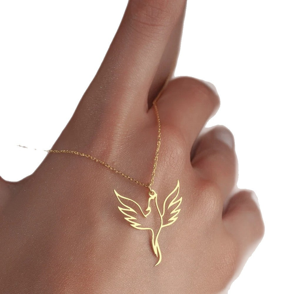 Gold bird-shaped necklace on a hand against a white background