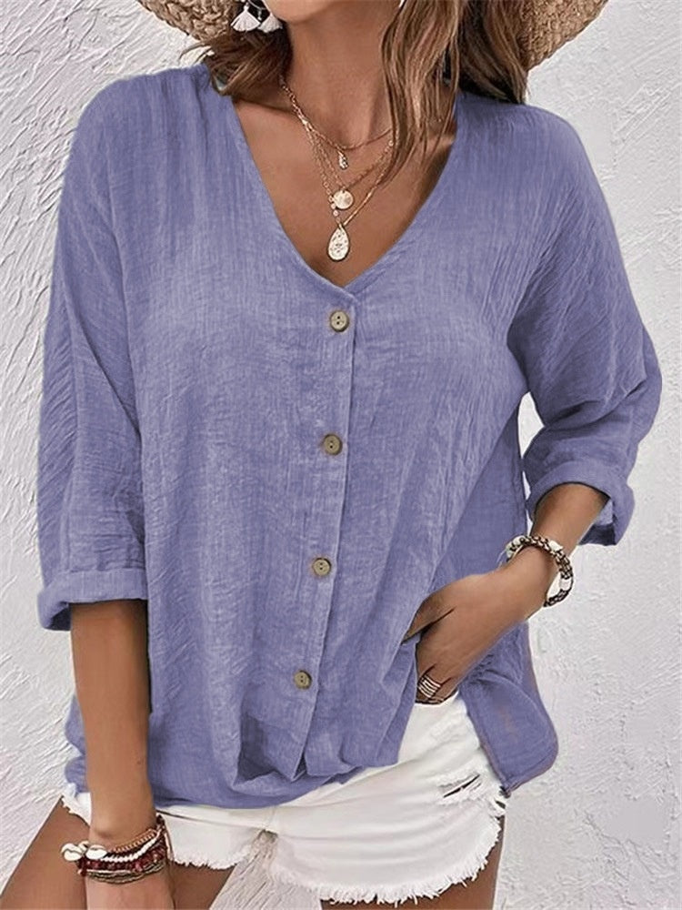 Woman wearing a blue button-up shirt and white shorts against a light gray background