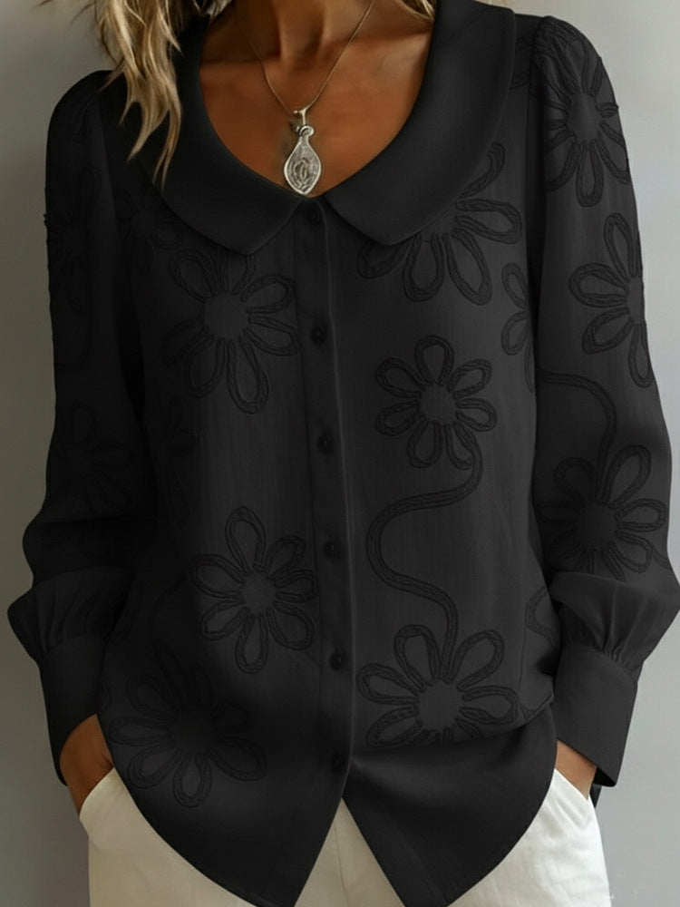 Black floral embroidered blouse worn by a person against a neutral background