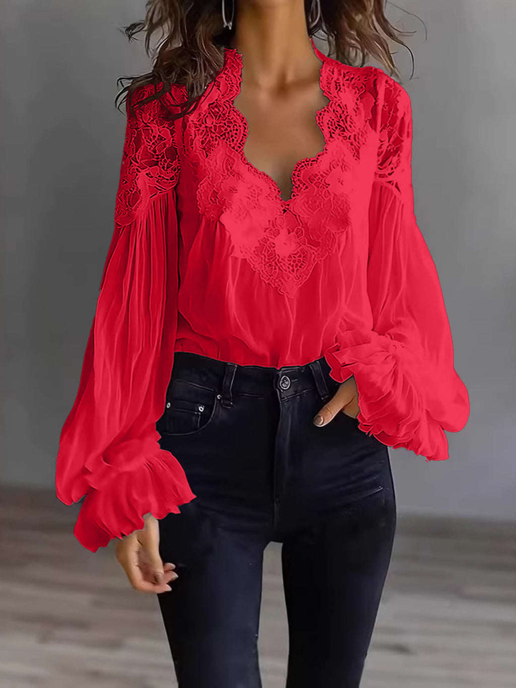 Red lace blouse with long sleeves worn by a person against a neutral background