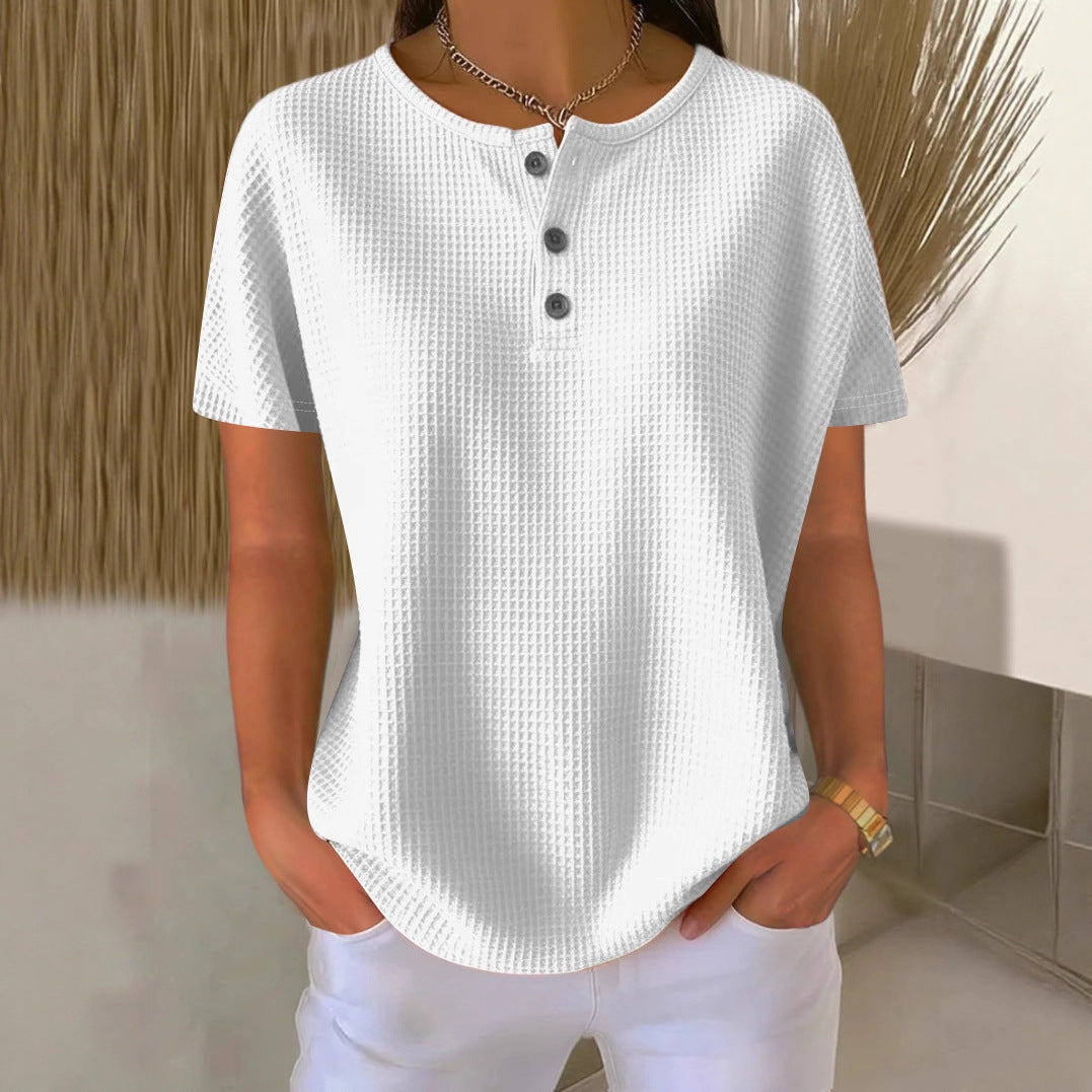 Person wearing a white textured shirt with black buttons in a minimalistic setting