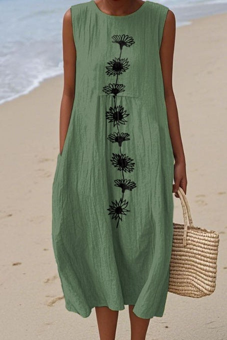Person wearing a green dress with black floral patterns on a beach.