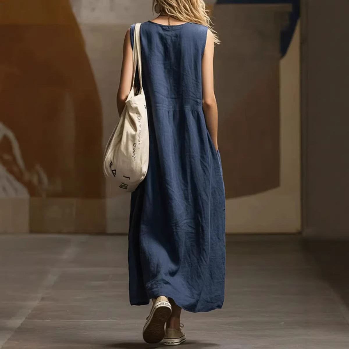 Person wearing a blue dress holding a beige bag in an indoor setting