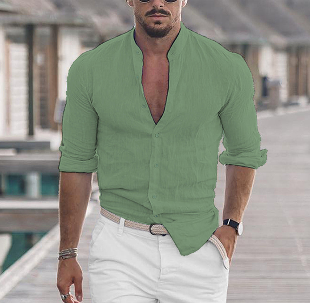 Man wearing a green shirt with rolled-up sleeves and white pants outdoors.