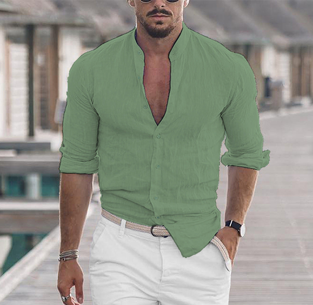 Man wearing a green shirt with rolled-up sleeves and white pants outdoors.