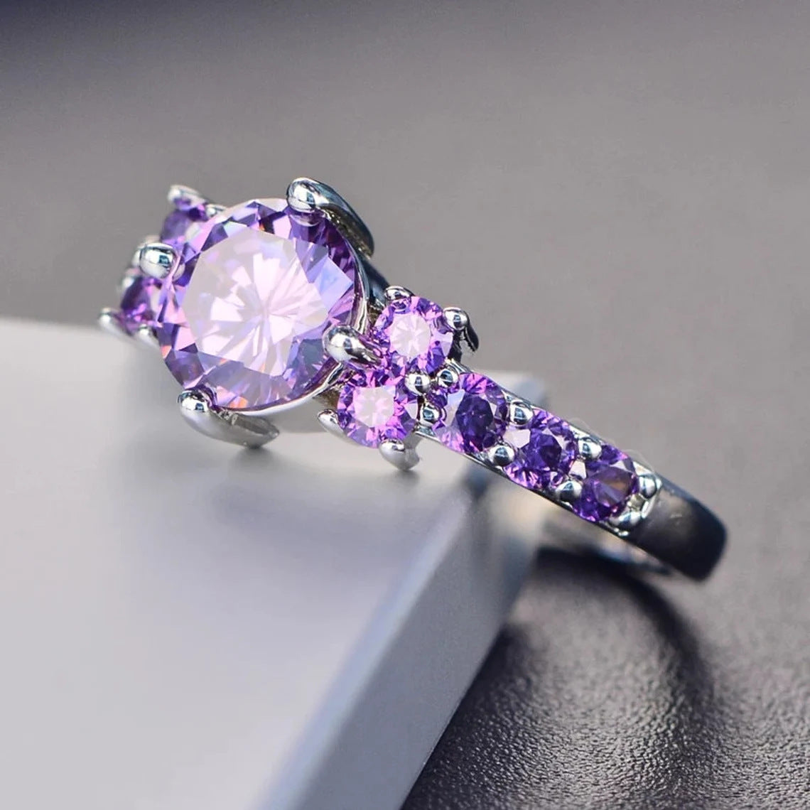 Purple gemstone ring with silver setting on a gray surface