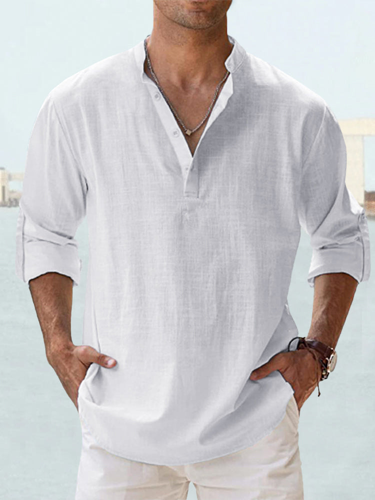 Man wearing a white linen shirt with rolled-up sleeves against a light blue background