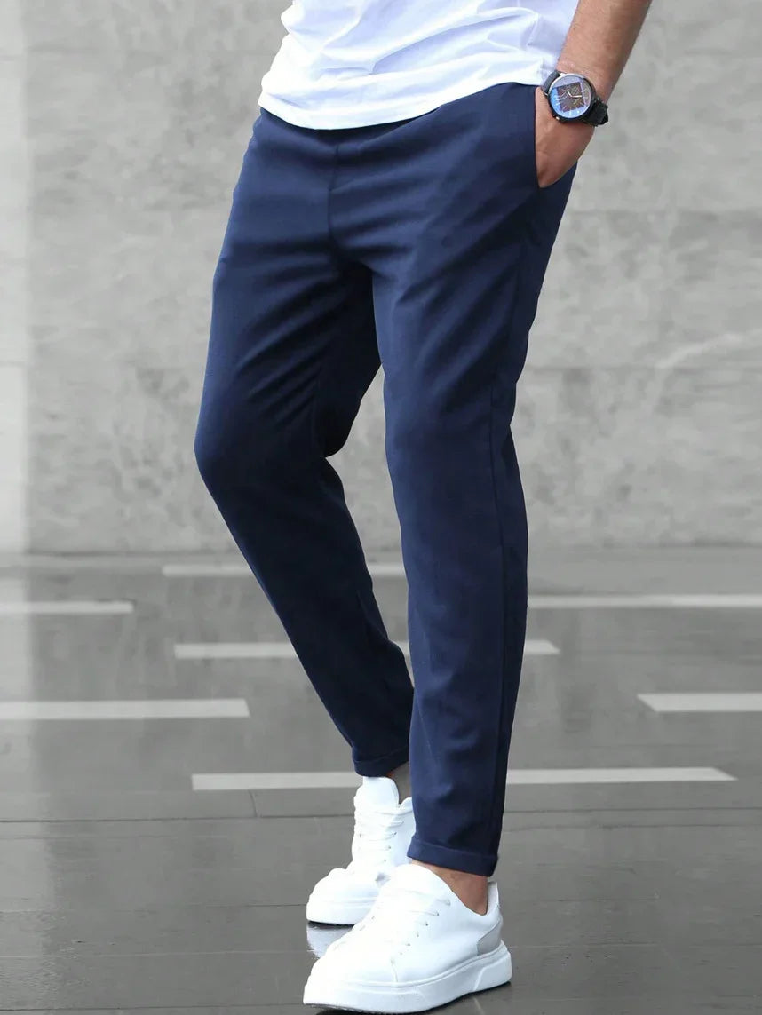 Person wearing navy pants and white sneakers on a gray floor.