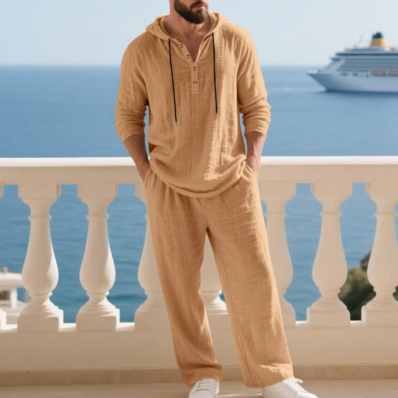 Man in beige outfit standing on a balcony with ocean and cruise ship in the background