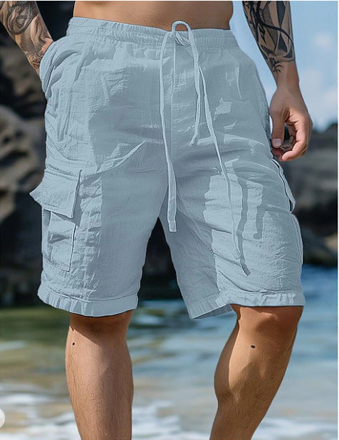 Person wearing light blue cargo shorts with a blurred beach background