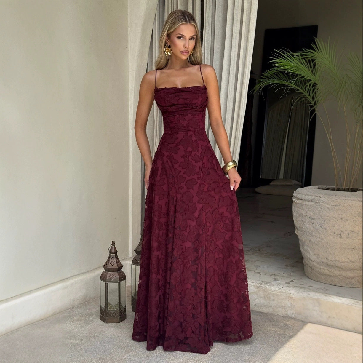 Woman wearing a burgundy lace dress standing in an indoor setting.
