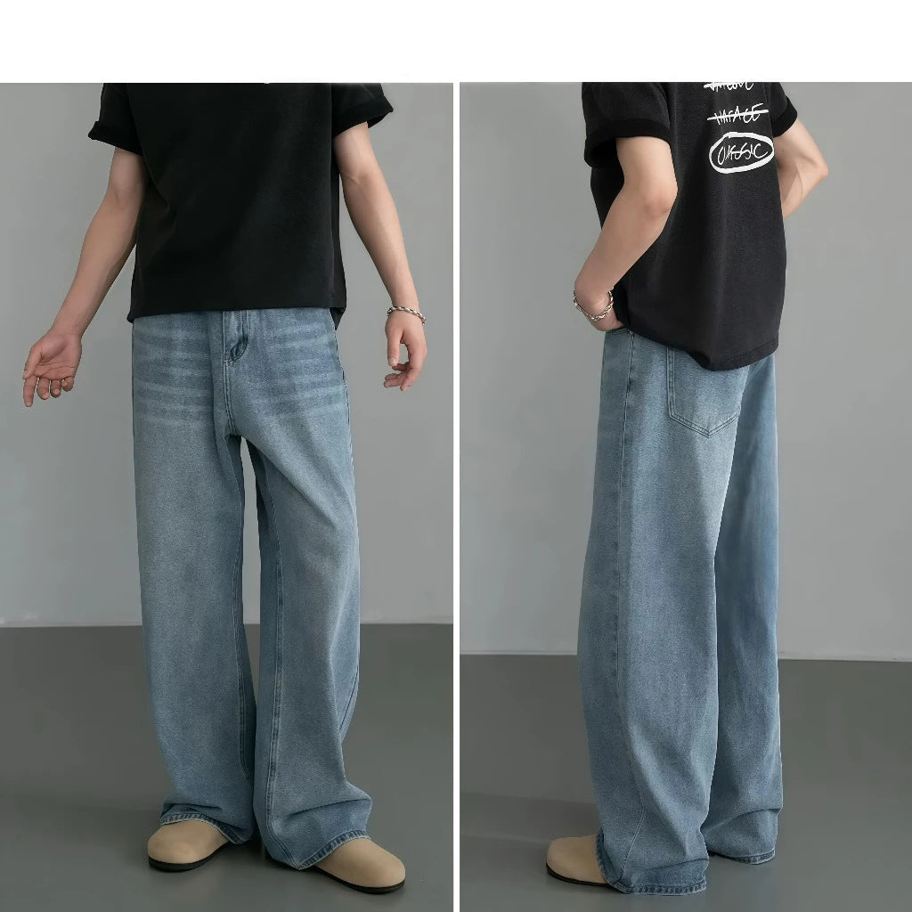 Person wearing blue jeans and a black t-shirt with a logo on a gray background