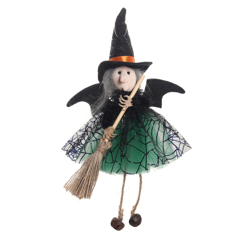 A decorative witch doll with a black pointed hat, black wings, a green tulle skirt with black spiderweb pattern, holding a straw broomstick, on a plain white background.