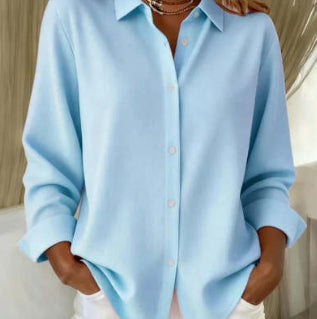Person wearing a light blue shirt with a blurred background