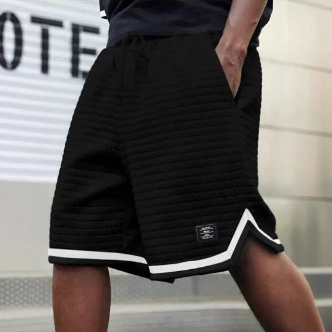 Black shorts with white trim worn by a person, blurred background