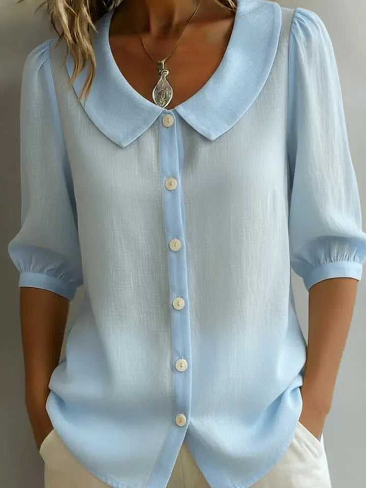 Light blue blouse with a collar and buttons on a neutral background