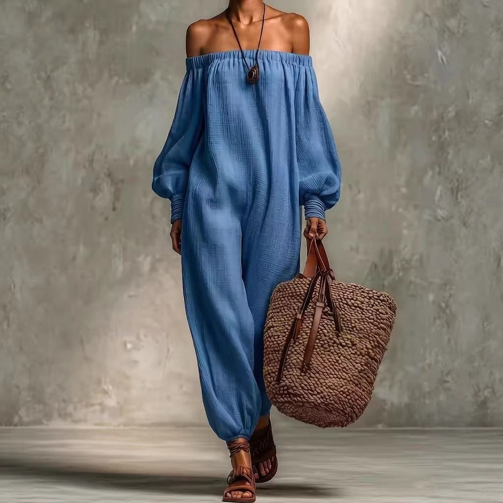 Person wearing a blue off-shoulder dress holding a brown woven bag against a gray background